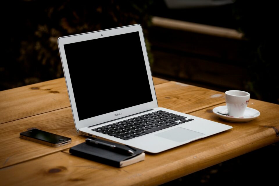 木の机の上にMacbookAirやメモ帳が置いてある