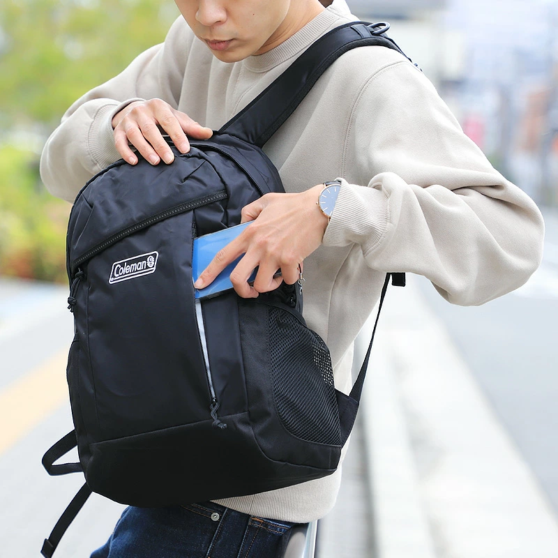 Colemanのリュックに荷物を入れる男性