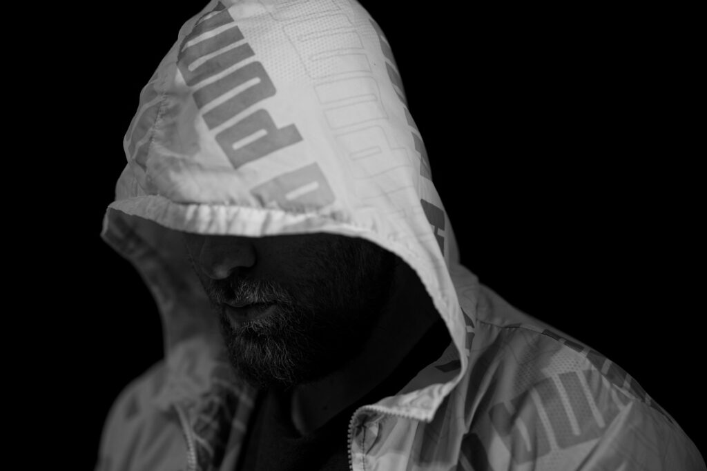 暗闇の中フードをかぶる男性