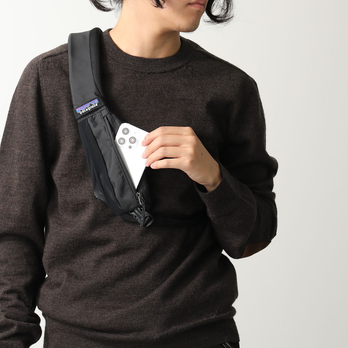 patagoniaのボディバッグからスマホを出す男性